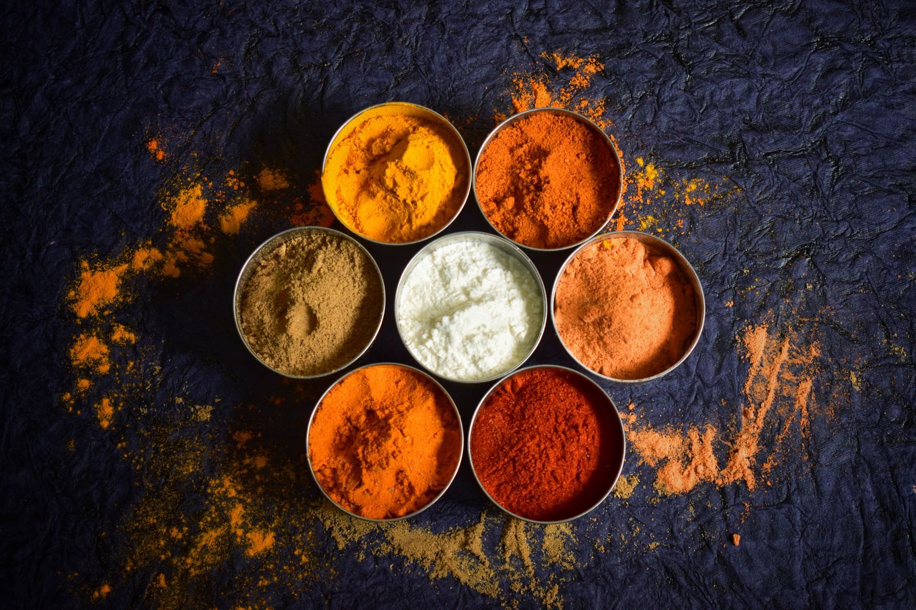 Colourful Indian spices in bowls on a textured dark background