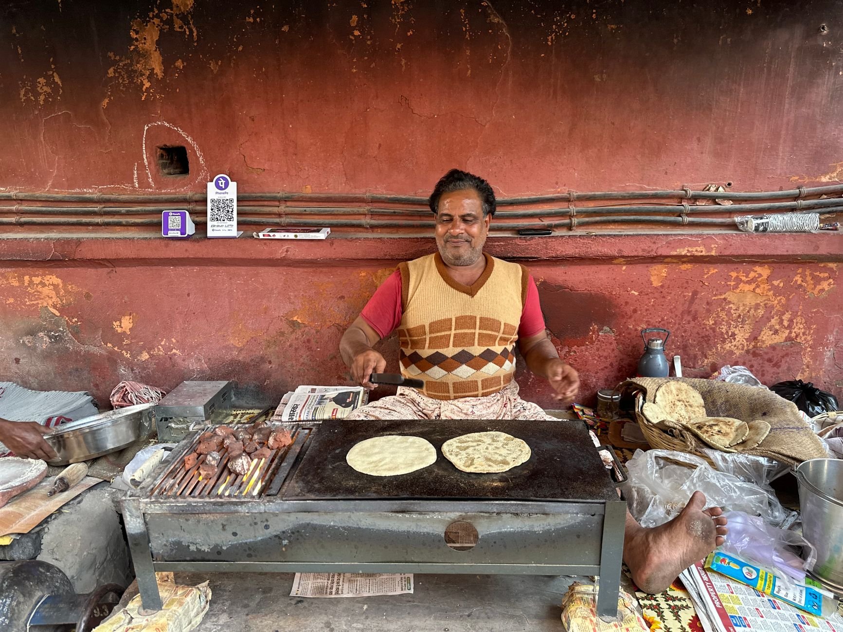 Street vendor cooking Indian flatbread on a griddle — the craft of live-fire cooking